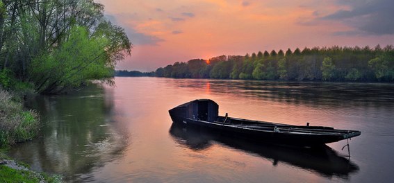 La douceur angevine : un bateau sur la Loire au couché du soleil.